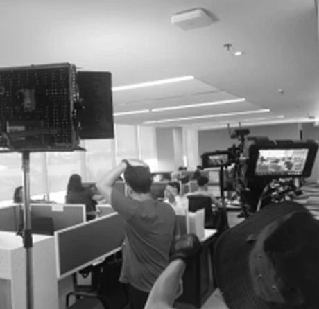 Behind the scenes of an office film shoot with a camera and lighting equipment